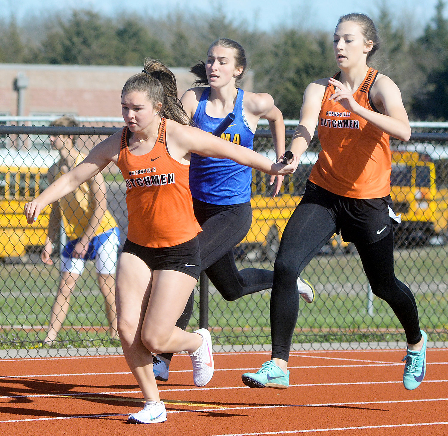 Alexis Kohrmann (far left) reaches back for the baton from Owensville Dutchgirl teammate Ella Gehlert during the girls 4x200-meter relay at the OHS Relays held earlier this spring.